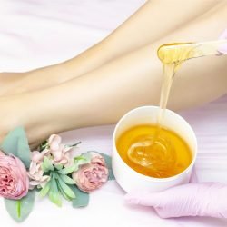 young woman having hair removal procedure on leg with sugaring paste in salon young woman having hair removal procedure on leg with sugaring paste in salon